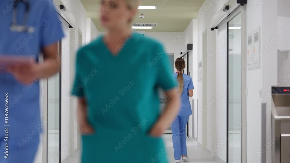 Medical professionals in scrubs walking and interacting in a modern hospital hallway, focusing on teamwork and a busy healthcare environment. Concept of professional healthcare staff collaboration Medical professionals in scrubs walking and interacting in a modern hospital hallway, focusing on teamwork and a busy healthcare environment. Concept of professional healthcare staff collaboration