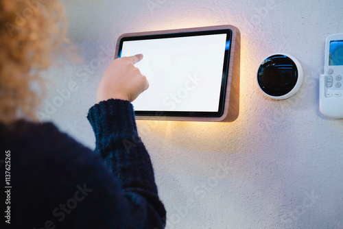 Young woman touching digital PC mounted on wall at home photo