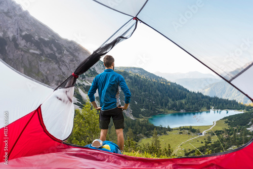 Austria, Tyrol, Hiker standing at his tent in the mountains, looking at Lake Seebensee photo