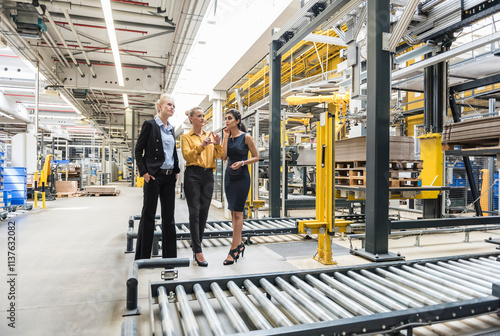 Wallpaper Mural Three women discussing at conveyor belt in factory Torontodigital.ca