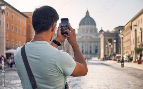 Young man clicking photos of St. Peter's Basilica through smart phone