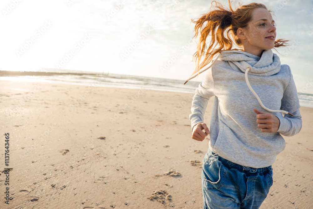 Netherlands, Zeeland, redheaded woman jogging on the beach Netherlands, Zeeland, redheaded woman jogging on the beach