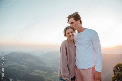 Switzerland, Grosser Mythen, portrait of happy young couple standing in mountainscape at sunrise