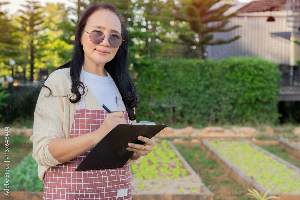 Portrait of mature Asian woman with checklist paper for harvesting fresh vegetable Portrait of mature Asian woman with checklist paper for harvesting fresh vegetable