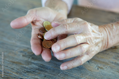 Hands of senior woman counting coins at table photo