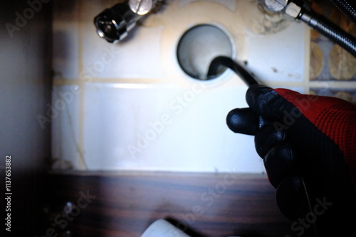 A plumber is trying to open a clogged bathroom pipe using a camera system. Close-up view of opening a clogged sewer drain with a robot. Handyman, repair and plumbing works.
 photo