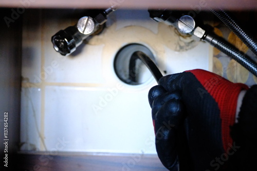 A plumber is trying to open a clogged bathroom pipe using a camera system. Close-up view of opening a clogged sewer drain with a robot. Handyman, repair and plumbing works.
