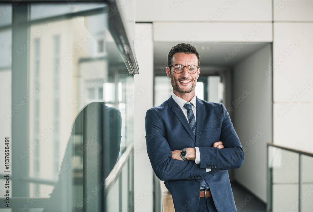 Portrait of a successful businessman, standing in office building, with arms crossed Portrait of a successful businessman, standing in office building, with arms crossed