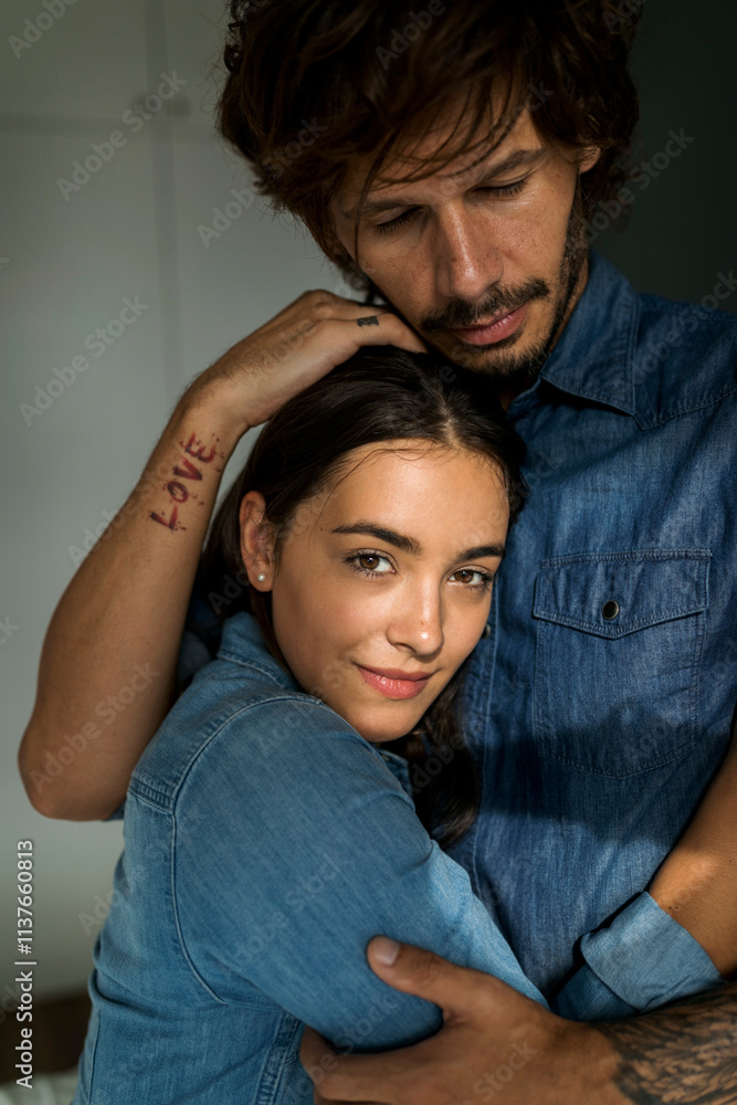Tattooed man embracing smiling girlfriend Tattooed man embracing smiling girlfriend