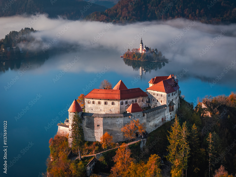 Bled, Slovenia - Aerial view of beautiful Bled Castle (Blejski Grad) with Lake Bled (Blejsko Jezero), the Church of the Assumption of Maria and Julian Alps at background on a foggy autumn morning