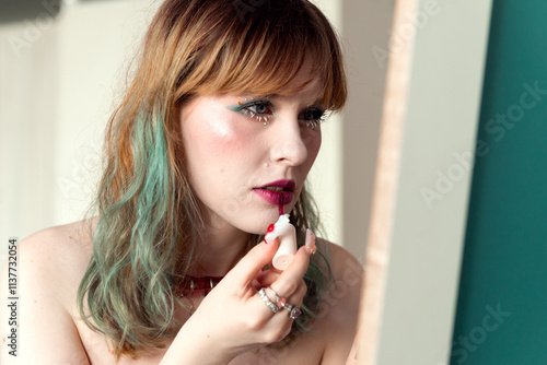 Woman Applying Lipstick in Bright Room with Natural Light photo