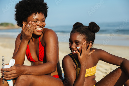 Tableau sur toile Happy family applying sun protection at the beach