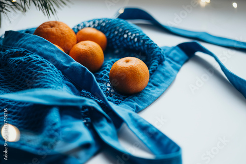 Fresh tangerines in a blue string bag on a light background photo