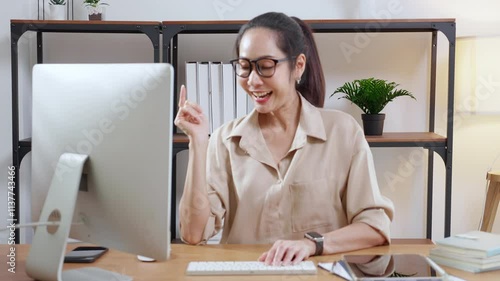 Young asian business woman using desktop computer while thinking for success in modern home office, businesswoman working with computer gesture glad in living room at home, business and freelance.