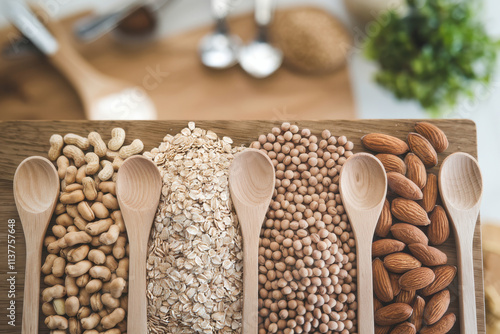 Wooden board featuring peanuts, oats, soybeans, and almonds with wooden spoons for cooking inspiration