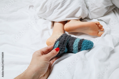 Mother's hand removing warm sock from child's foot photo