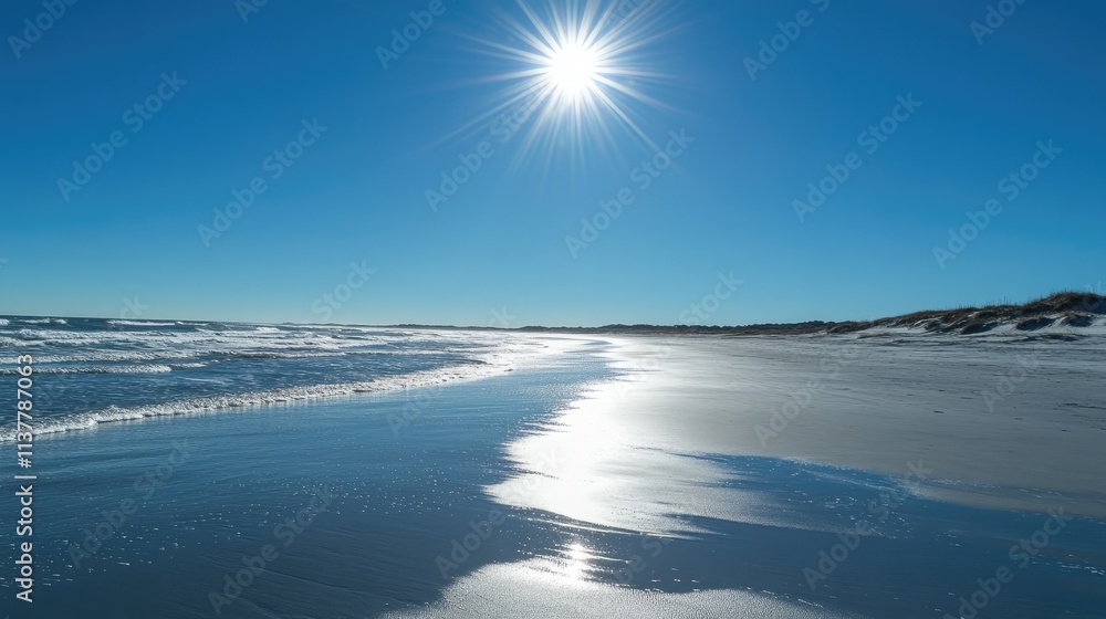 Fototapeta premium A clear and bright midday sky with the sun shining brightly over a sandy beach and turquoise waves.