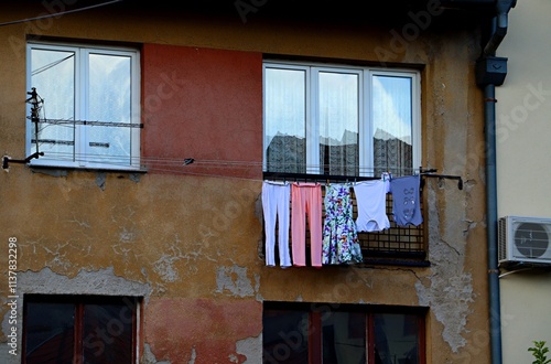 Washed laundry hangs to dry on a line stretched under the windows on the second floor of a detached house. photo