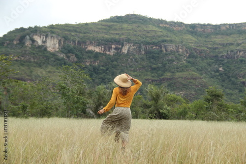 mulher de saia longa e chapéu correndo com serra de santo antonio ao fundo em campo maior, piauí  photo