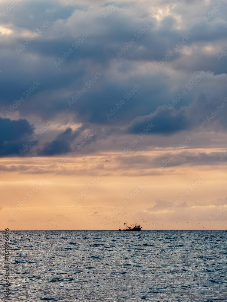 Fototapeta premium Fishing boat at dramatic sunset on Black Sea coast