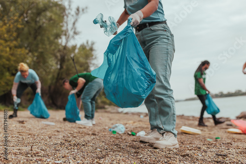 Volunteers collecting garbage on river bank wearing gloves