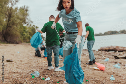 Принти на полотні Volunteers cleaning a polluted river bank: teamwork and environmental protection