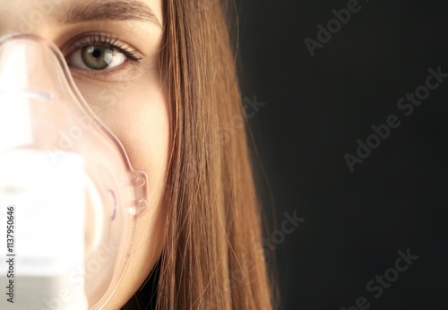 A young woman with a portable inhaler.Portrait of a young woman doing inhalation at home. Use nebulizer and inhaler for the treatment.