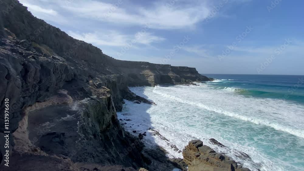 Dramatic coast in the small village of Puertito de Los Molinos on Fuerteventura island is home to a lovely beach and some caves that can only be accessed at low tide. Dramatic coast in the small village of Puertito de Los Molinos on Fuerteventura island is home to a lovely beach and some caves that can only be accessed at low tide.