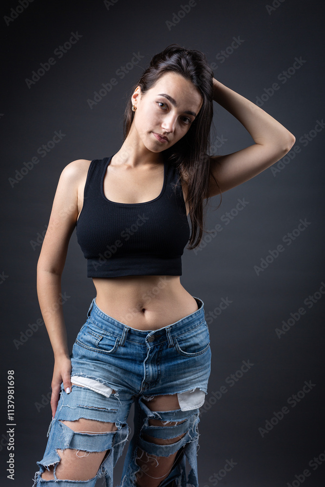 A beautiful brunette poses in the studio wearing a top and jeans. A beautiful brunette poses in the studio wearing a top and jeans.