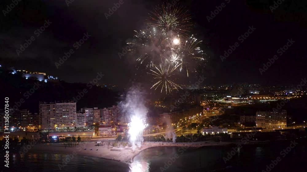 Nocturne aerial view of the fireworks launched in the beach of El Postiguet, in the Mediterranean city of Alicante, Spain. Nocturne aerial view of the fireworks launched in the beach of El Postiguet, in the Mediterranean city of Alicante, Spain.