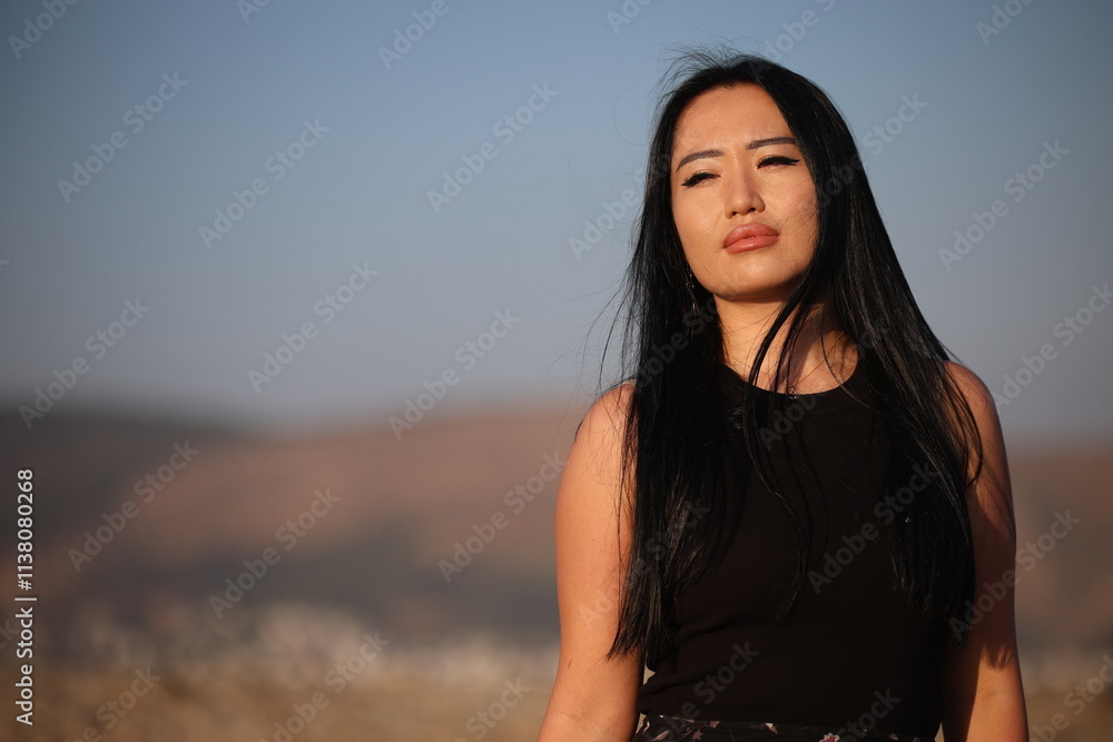 Fototapeta premium A joyful young Asian woman embraces the breathtaking beauty of her surroundings during the golden hour. 