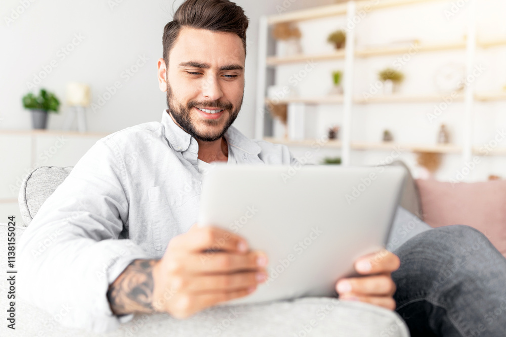 Closeup of caucasian man resting on sofa with digital tablet, home interior, free space. Happy guy sitting on couch in living room, using nice mobile app on modern pad, copy space Closeup of caucasian man resting on sofa with digital tablet, home interior, free space. Happy guy sitting on couch in living room, using nice mobile app on modern pad, copy space