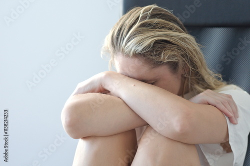 Woman with head down, arms crossed, expressing sadness and despair, copy space photo