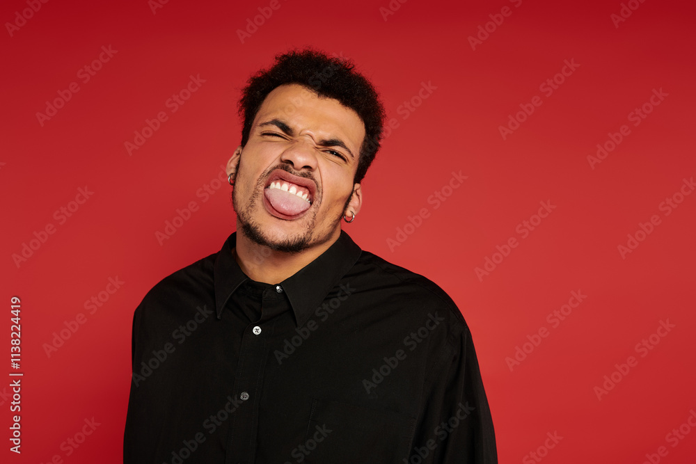 Obraz premium A charming young man poses playfully, showcasing his fun personality in front of a bright backdrop.