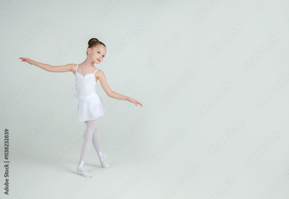 A little adorable young ballerina poses on camera. Ballet school concept. Studio portrait A little adorable young ballerina poses on camera. Ballet school concept. Studio portrait