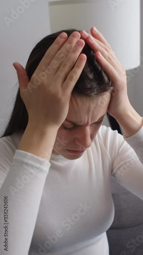 Wallpaper Mural Vertical footage of stressed young woman touching head and feels dizzy, suffering from headache and migraine pain, sitting alone on couch at home, tired and exhausted lady feels bad. Crisis concept Torontodigital.ca
