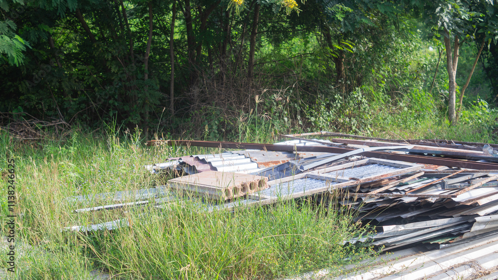 Zinc for roofing and old steel They were left together in a pile on the grassy area with tall grass. Construction material concept Zinc for roofing and old steel They were left together in a pile on the grassy area with tall grass. Construction material concept