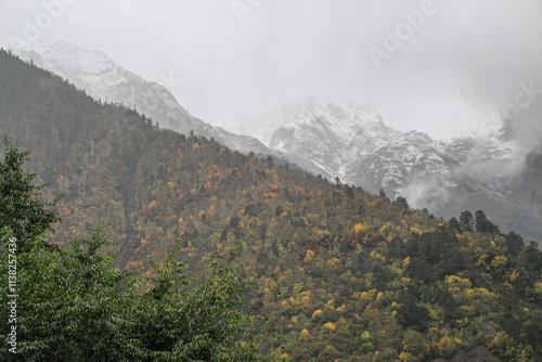 Melting Glacier in the clouds among green hills in Mingyong, Yunnan, China, and Buddhist prayer flags on the top of the mountain. Meili(Meri) Snow Mountains scenery- Mingyong Glacier.  photo