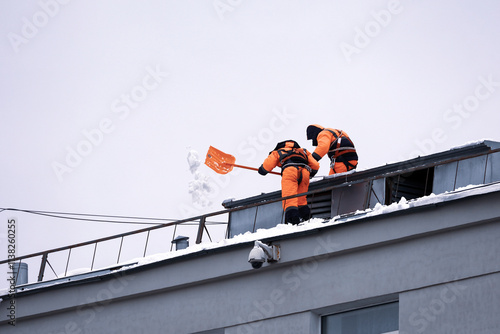 Obraz na płótnie Workers removing snow on the roof of a building