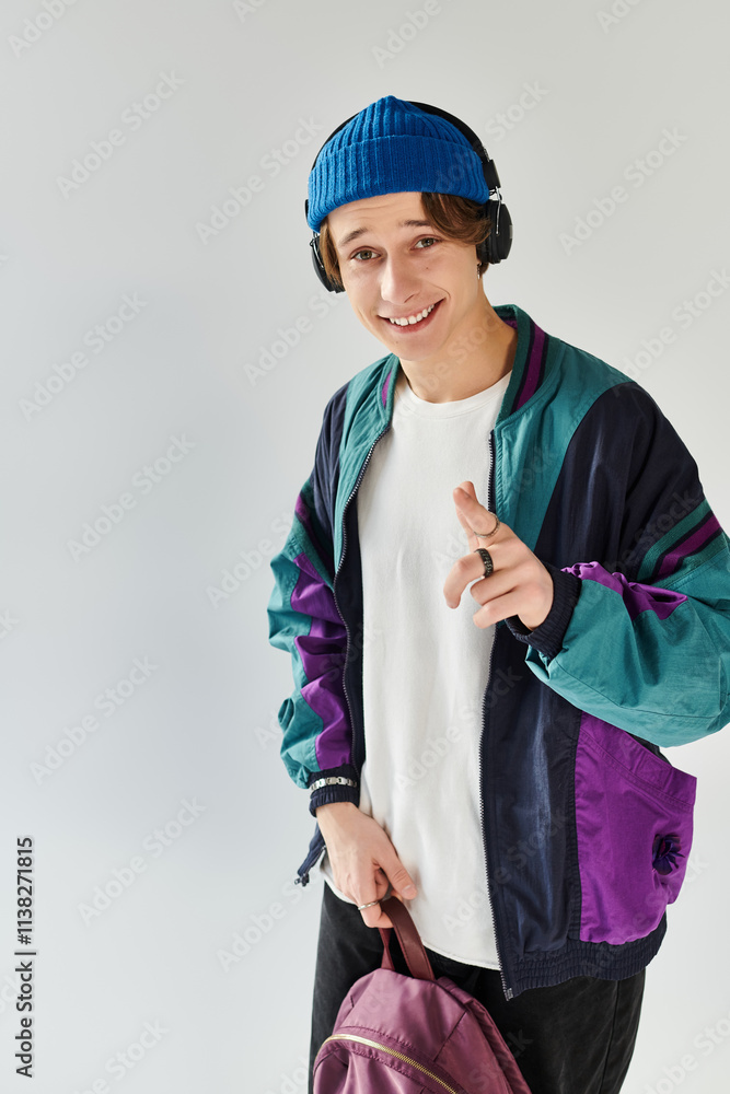A handsome young man wears a stylish bomber jacket and beanie while smiling in a bright studio. A handsome young man wears a stylish bomber jacket and beanie while smiling in a bright studio.