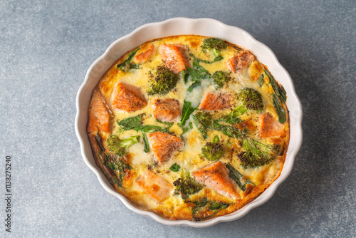 Egg-based frittata, omelette with salmon, broccoli and spinach. Italian dish, crustless quiche with eggs, fish and vegetables.