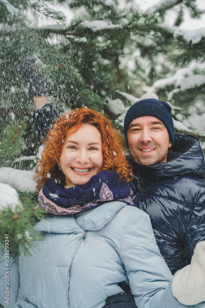 Obraz premium Love romantic love story. Happy couple of middle aged millennials, bright red-haired woman in winter snow park. Romantic date, kissing, hugging. Walking, having fun. Stylish blue clothes, jacket, hat
