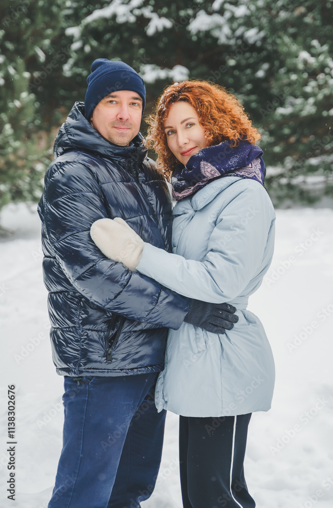 Love romantic love story. Happy couple of middle aged millennials, bright red-haired woman in winter snow park. Romantic date, kissing, hugging. Walking, having fun. Stylish blue clothes, jacket, hat Love romantic love story. Happy couple of middle aged millennials, bright red-haired woman in winter snow park. Romantic date, kissing, hugging. Walking, having fun. Stylish blue clothes, jacket, hat