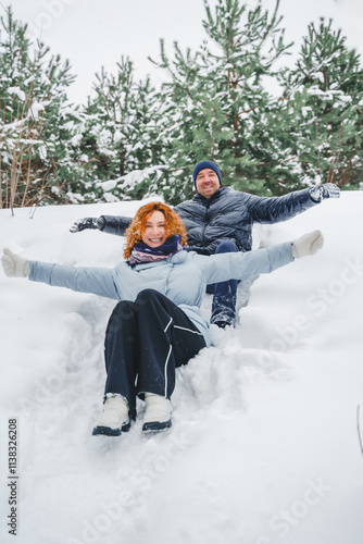 Love romantic love story. Happy couple of middle aged millennials, bright red-haired woman in winter snow park. Romantic date, kissing, hugging. Walking, having fun. Stylish blue clothes, jacket, hat