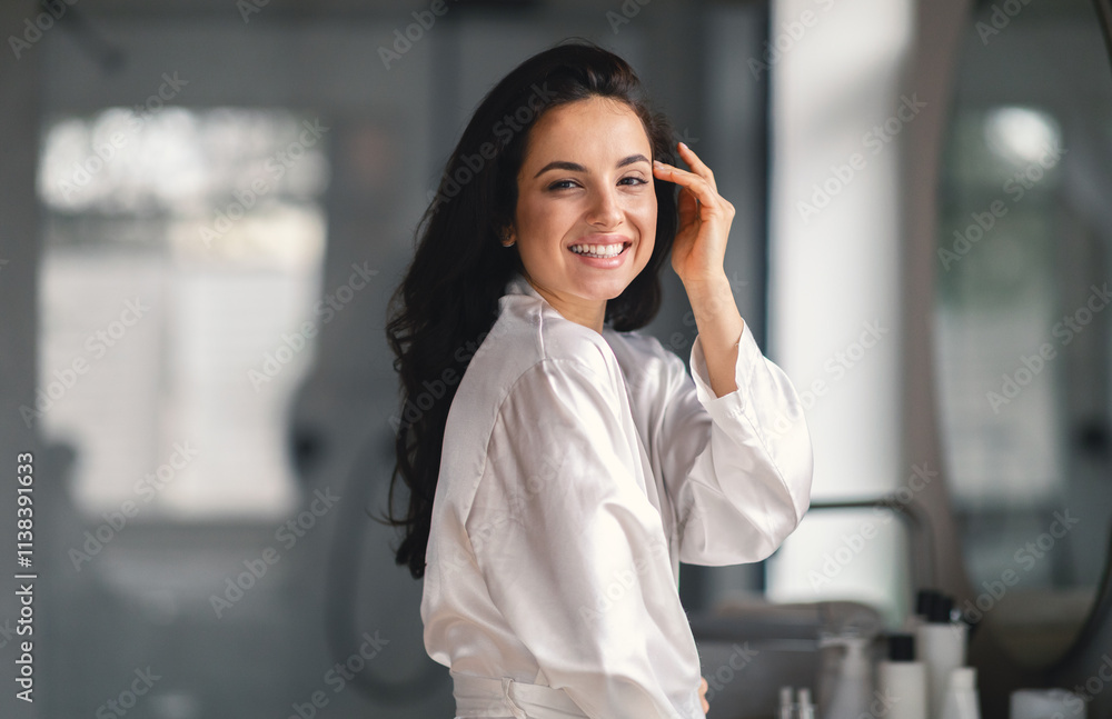 A young brunette woman smiles radiantly while pampering herself with skincare products in a modern bathroom. Natural light enhances her beauty as she engages in self-care. A young brunette woman smiles radiantly while pampering herself with skincare products in a modern bathroom. Natural light enhances her beauty as she engages in self-care.