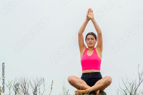 Mujer Delgada Sentada en una Roca Bajo el Cielo Nublado. Mujer delgada en top y short haciendo ejercicio en medio de un paisaje natural, perfecta representación de conexión con la naturaleza y cuidado photo