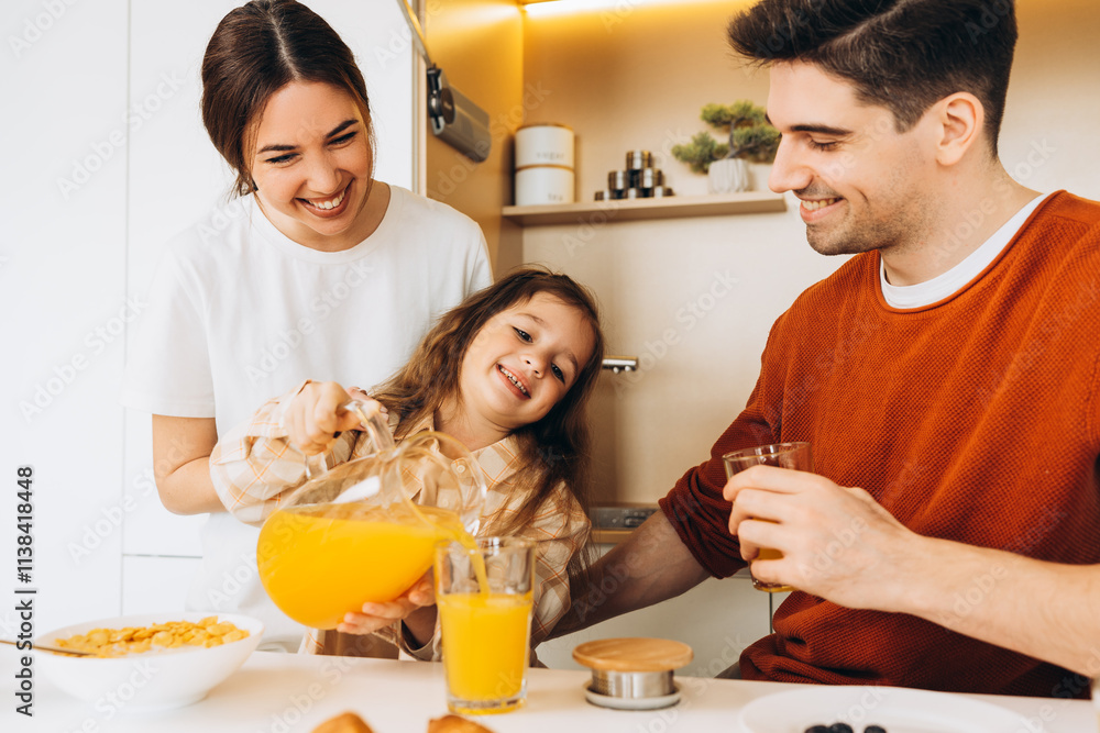 Happy family enjoying orange juice during breakfast in kitchen Happy family enjoying orange juice during breakfast in kitchen