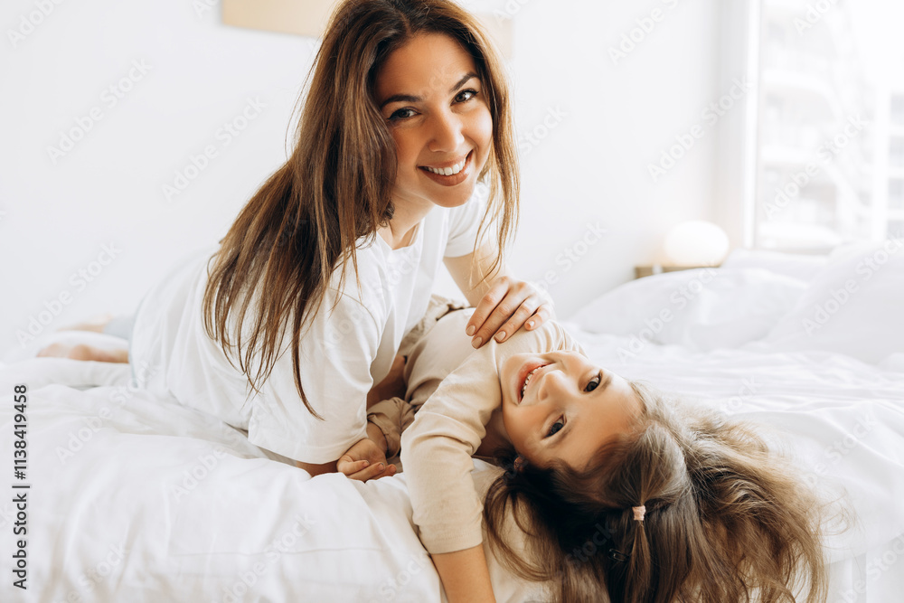 Happy mother and daughter playing on bed in bedroom Happy mother and daughter playing on bed in bedroom