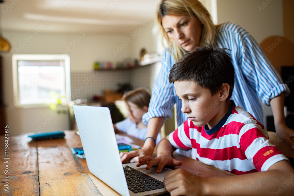 Mother helping son with homework on laptop in kitchen Mother helping son with homework on laptop in kitchen
