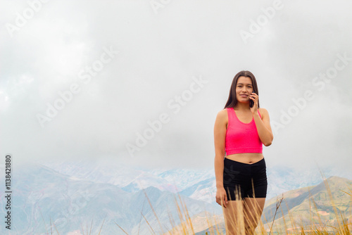 una mujer atractiva con top y short sosteniendo un teléfono celular en la mano en el campo, una linda chica mirando la pantalla del móvil. representación de conexión con la naturaleza photo